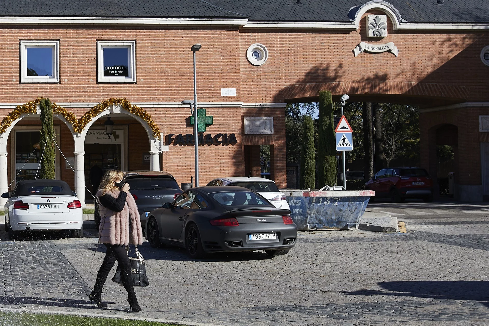 Una persona camina al lado de varios vehículos que cruzan una de las entradas a La Moraleja (Fuente: Agencias)