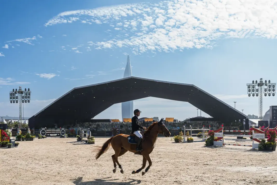 Escena de competición ecuestre con caballo y jinete con un fondo de anfiteatro moderno.